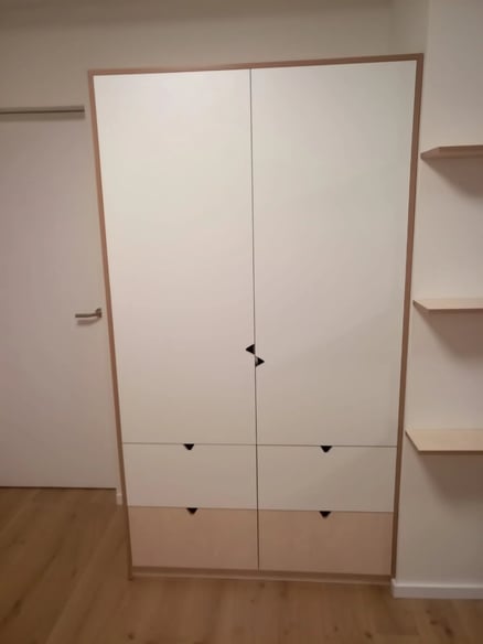 Minimalistický interiér s bílou skříní a dřevěnými prvky.